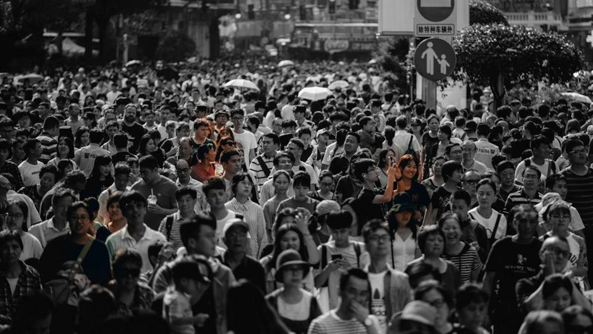 A large crowd photographed in black and white, with a few individuals left in color, representing the minority who develop addiction.