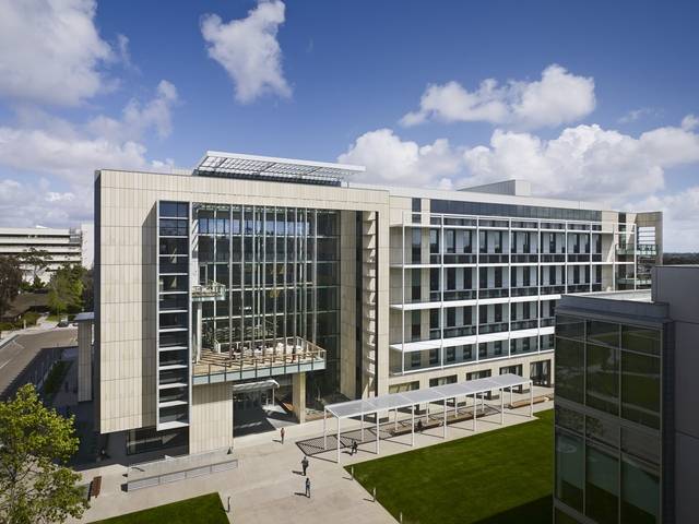 The Health Sciences Biomedical Research Facility at UC San Diego, a modern stone and glass laboratory building under a blue sky.